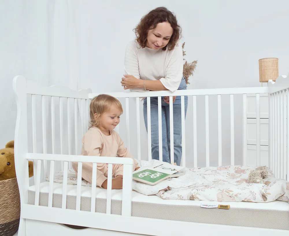 Fizjoterapeutka przy łóżeczku z materacem Fizjomax Baby i dzieckiem